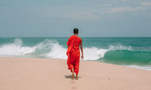 Young monk walking towards the sea